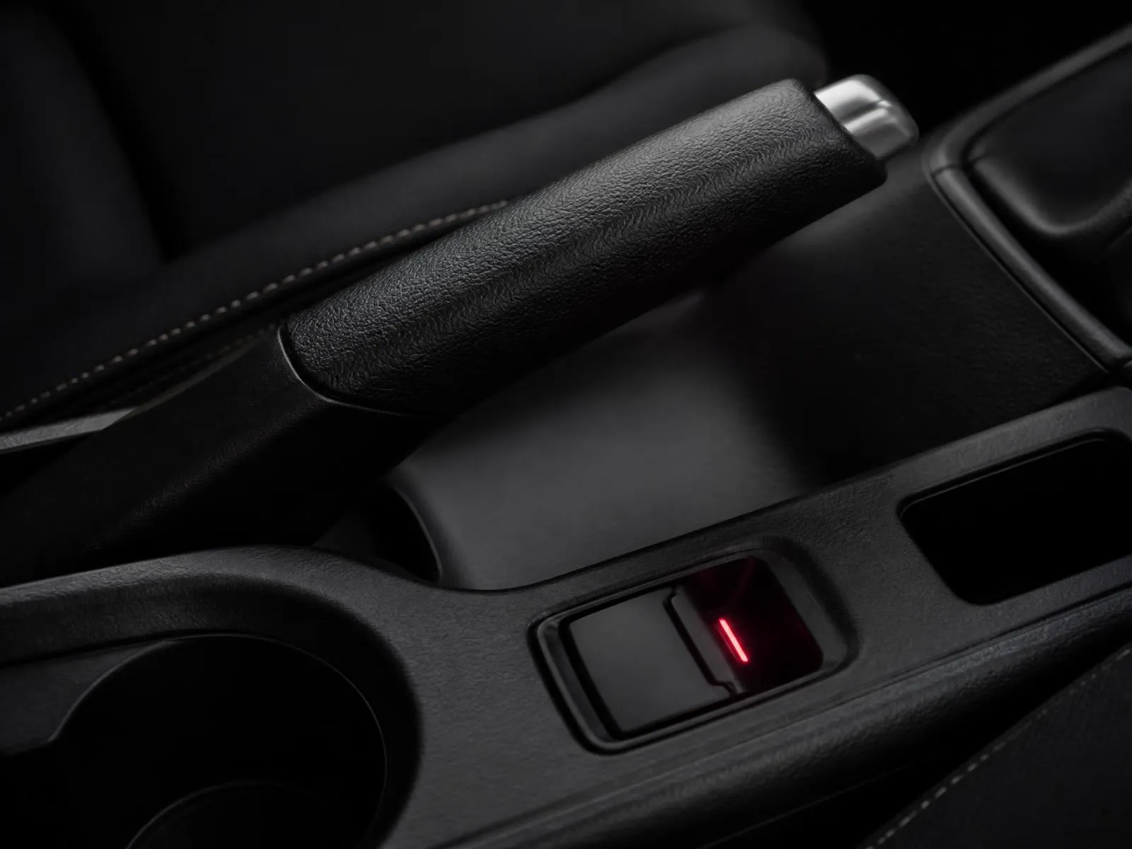 Páka ručnej brzdy a spínač elektrickej parkovacej brzdy na tmavej stredovej konzole